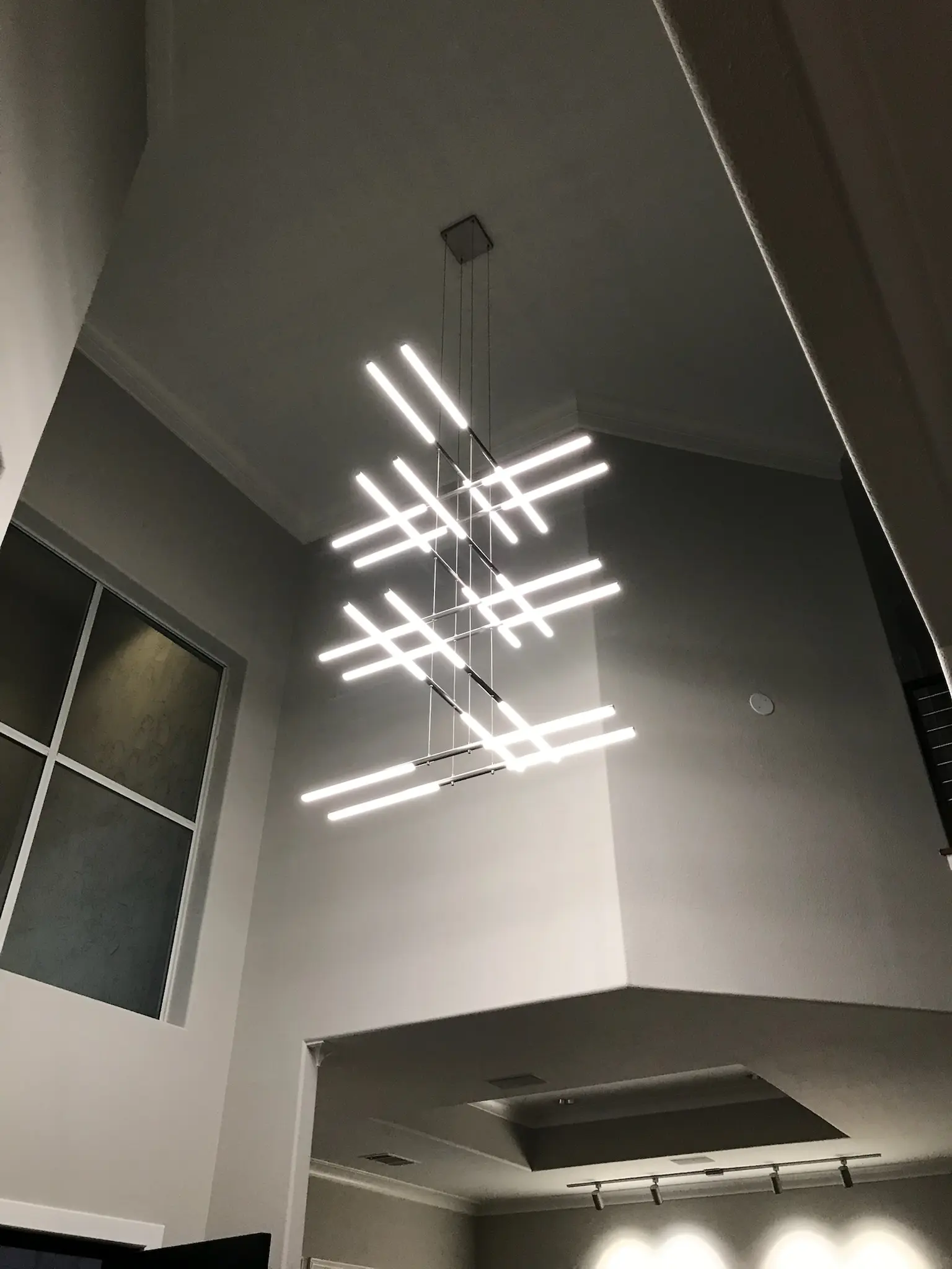 Bright contemporary interior with modern chandelier and energy-efficient window in a high-ceiling Plano home
