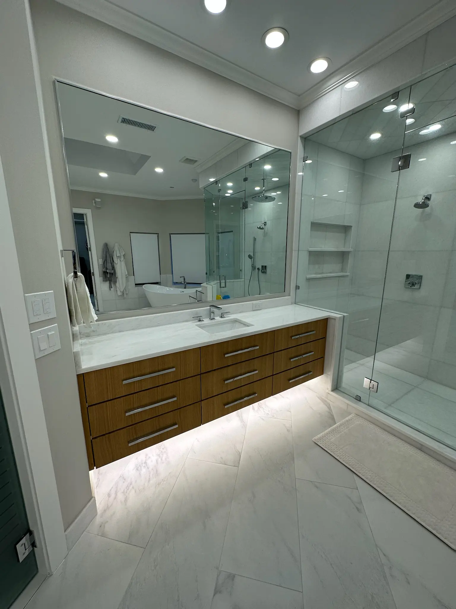 Modern luxury bathroom with floating vanity, marble countertops, and glass shower enclosure showcasing bathroom remodel cost in Plano