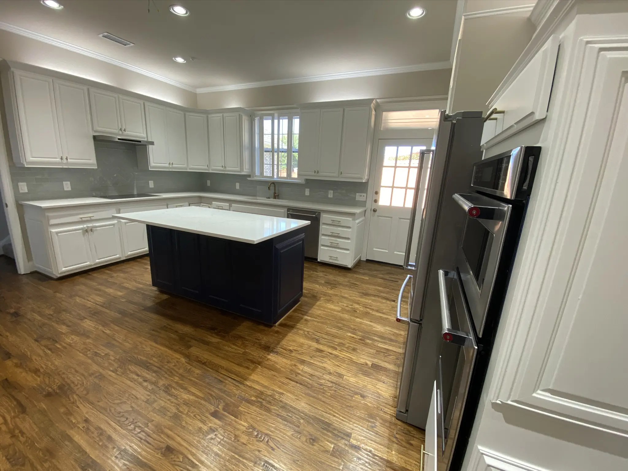 Luxury kitchen remodeling Plano & Far North Dallas featuring custom white cabinetry, hardwood floors, and a modern center island - Home Platinum Services.