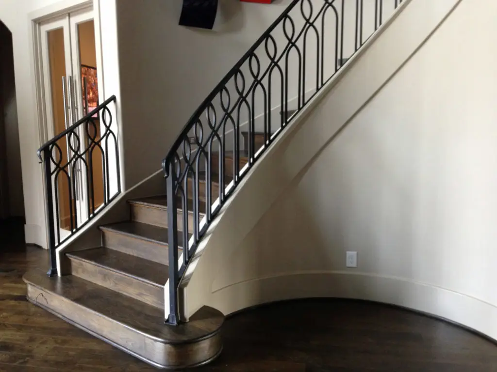 Curved staircase with dark wood steps and decorative black iron railing remodeling in Plano, Frisco, Dallas.