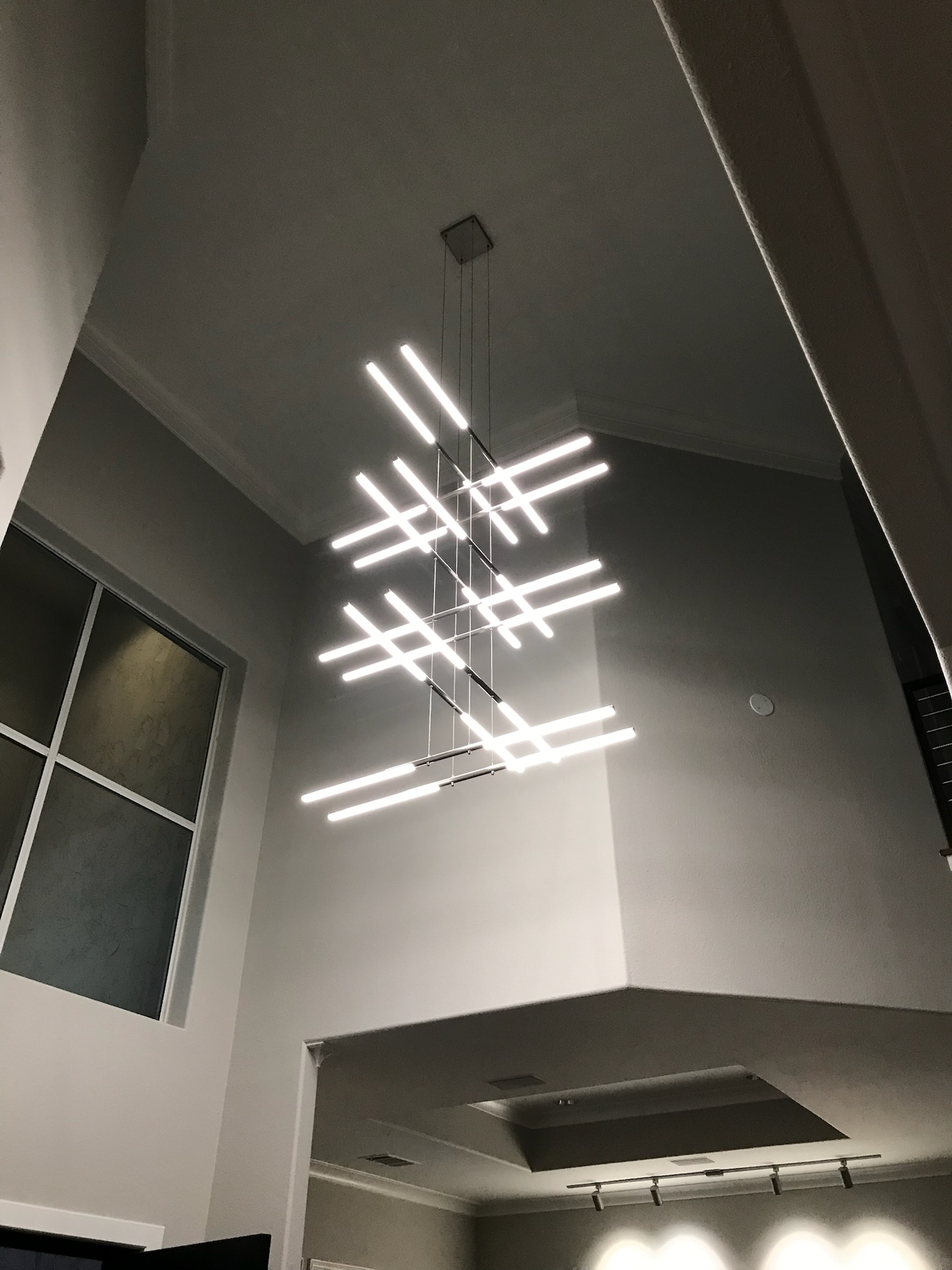 Bright contemporary interior with modern chandelier and energy-efficient window in a high-ceiling Plano home