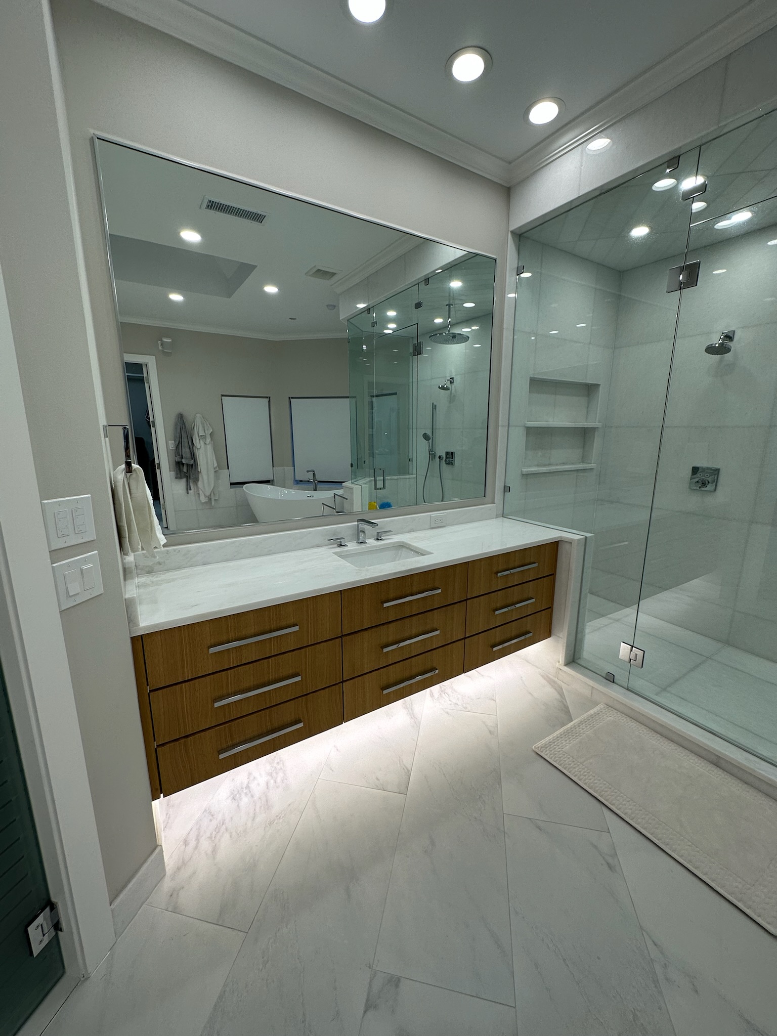 Modern luxury bathroom with floating vanity, marble countertops, and glass shower enclosure showcasing bathroom remodel cost in Plano