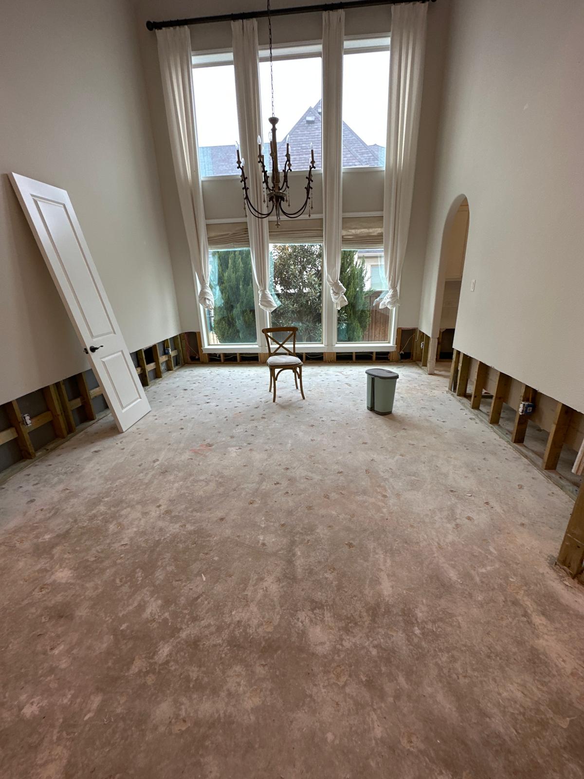 Living room with insurance water damage restoration in progress, showing removed drywall and flooring after flooding, representing insurance-covered water damage restoration services in Plano and Dallas, TX.
