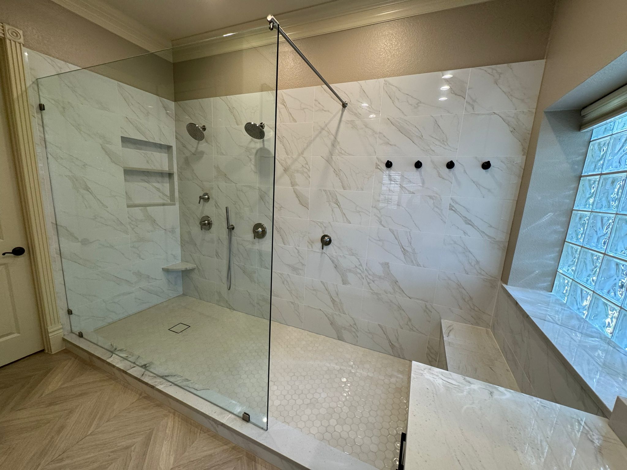 Modern full bathroom remodel featuring a spacious walk-in shower with glass enclosure, dual showerheads, and marble-style tile design, showcasing the value of converting a half bath to a full bath in Plano homes.