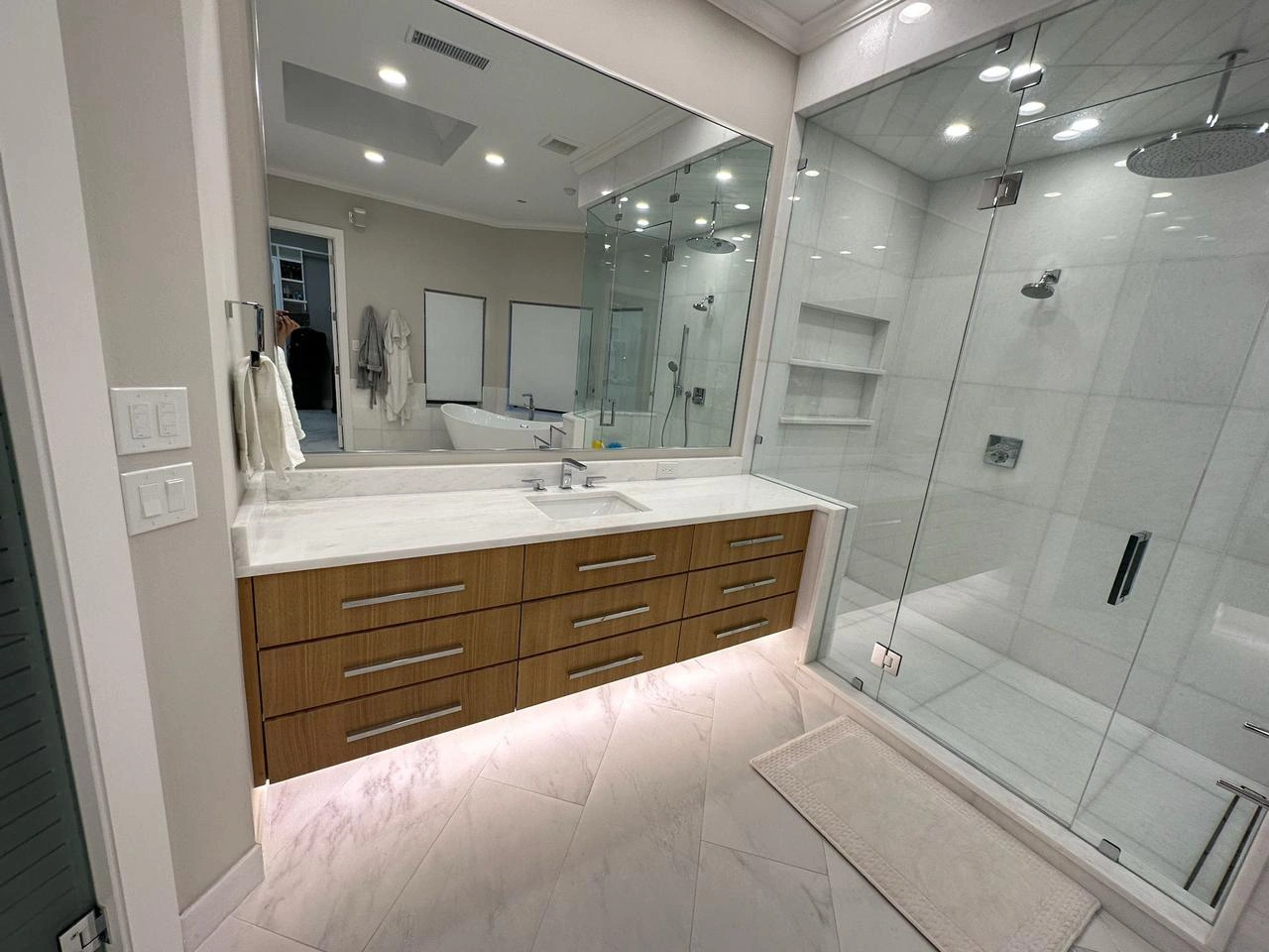 Sleek modern luxury Bathroom Remodeling Plano TX featuring a frameless glass shower, floating vanity with LED lighting, and marble-style tile flooring.