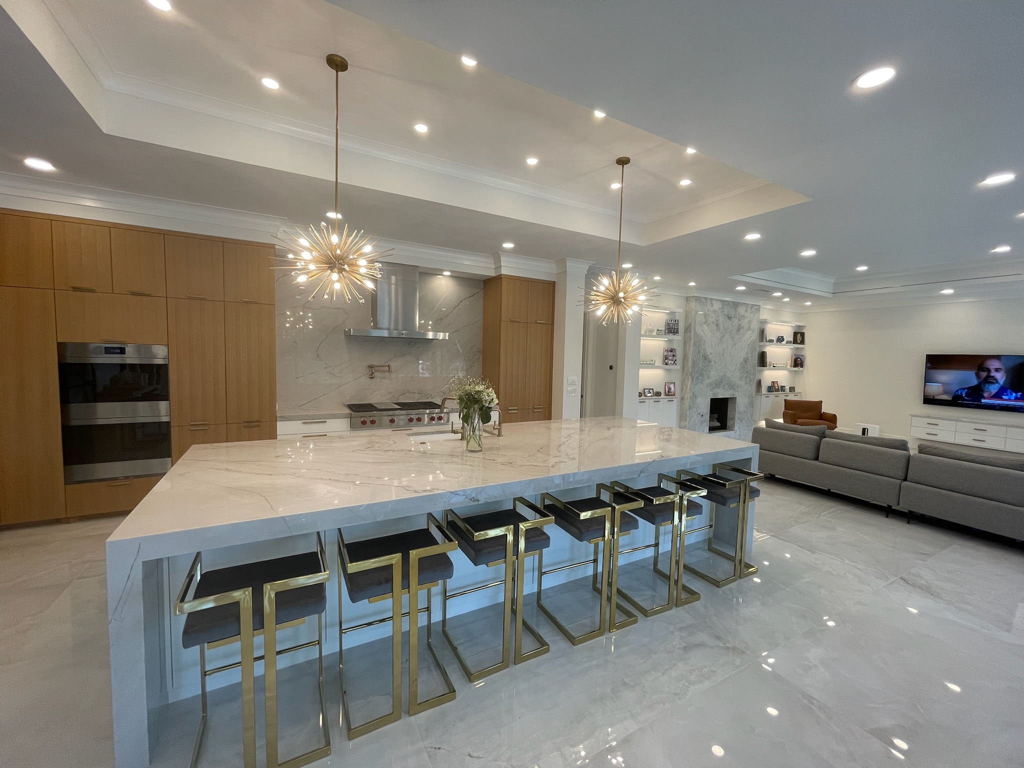 Open-concept luxury kitchen renovation with marble island, gold bar stools, and custom wood cabinetry in Plano, TX home remodeling project by Home Platinum Services.