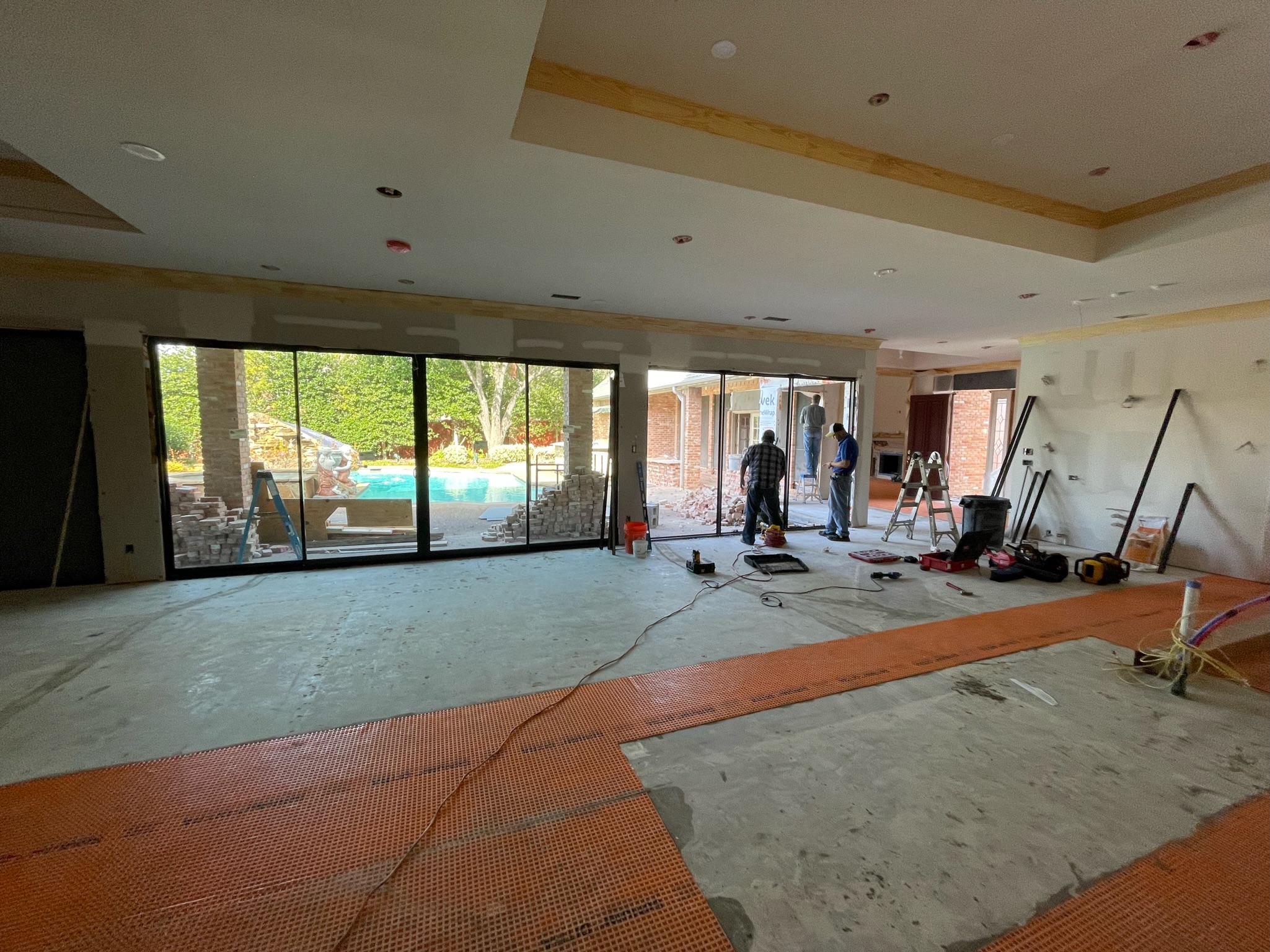 A spacious Plano home undergoing a full interior renovation with contractors installing large sliding doors and flooring, showcasing the work of leading Home Remodeling Contractors in Plano.